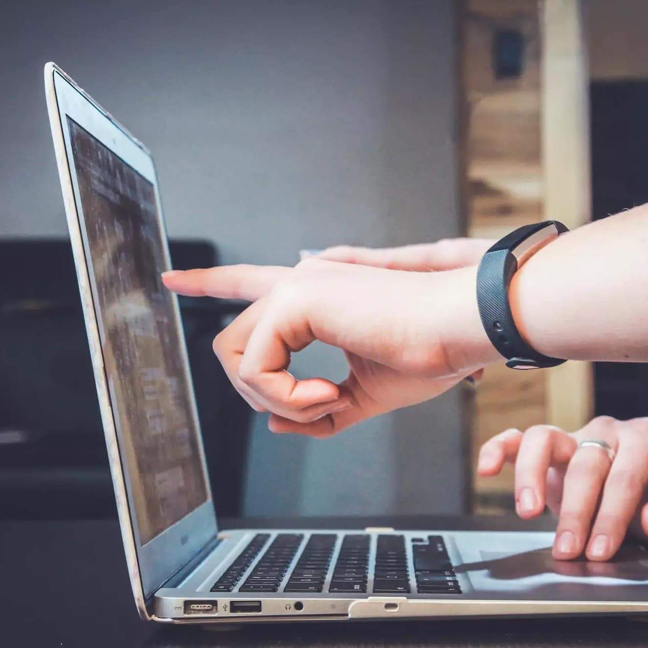 Hand pointing at a laptop screen