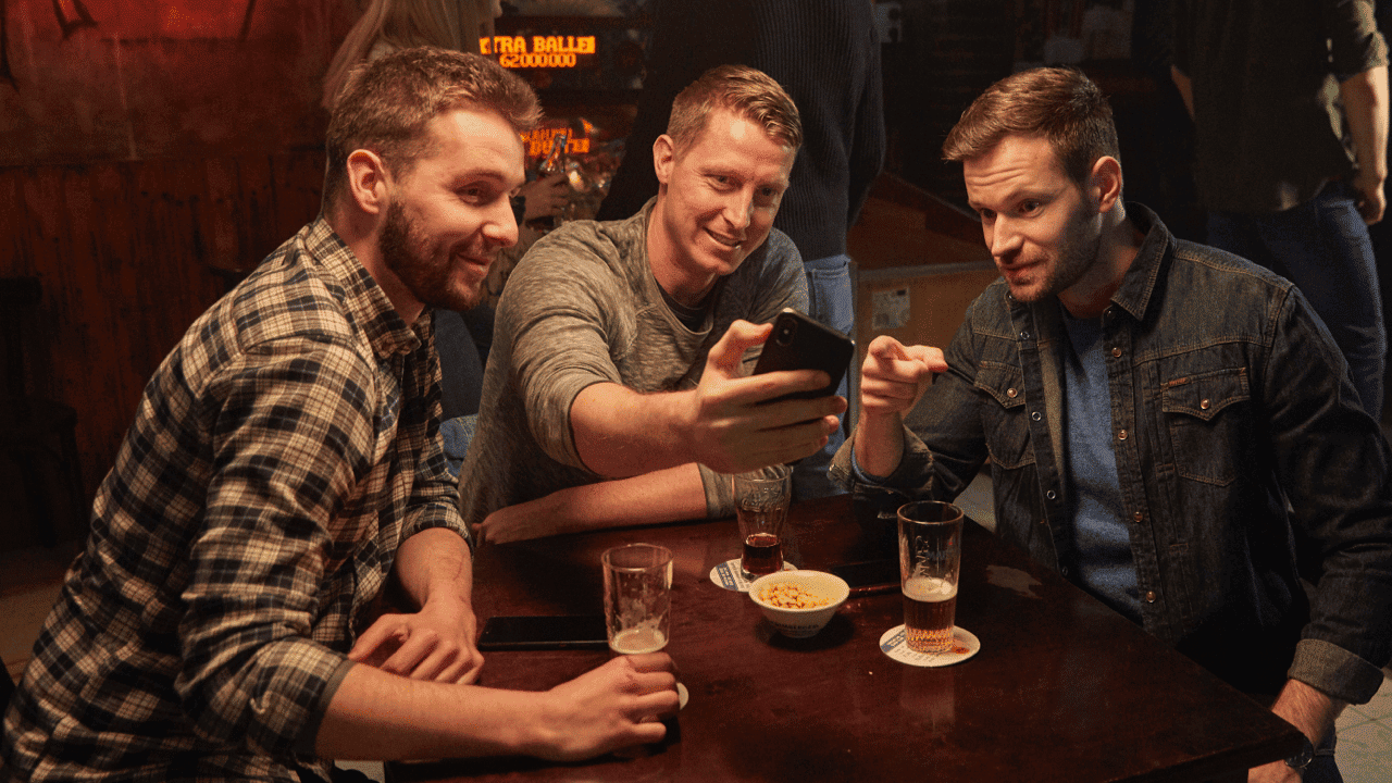 Friends playing Gouden Spelen on a phone in a bar